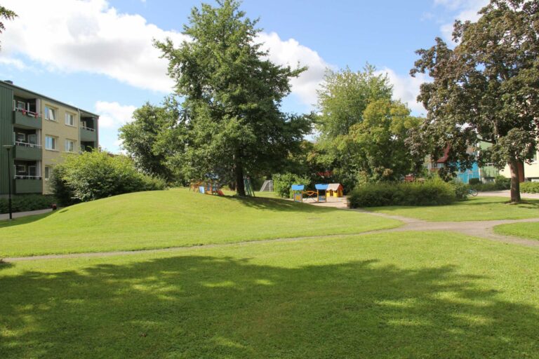 Grönyta med lekpark intill lägenhetshus i Hallstahammar centrum