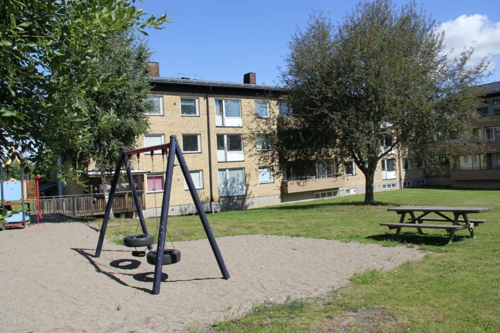 Lekpark med gungor utanför lägenhetshus