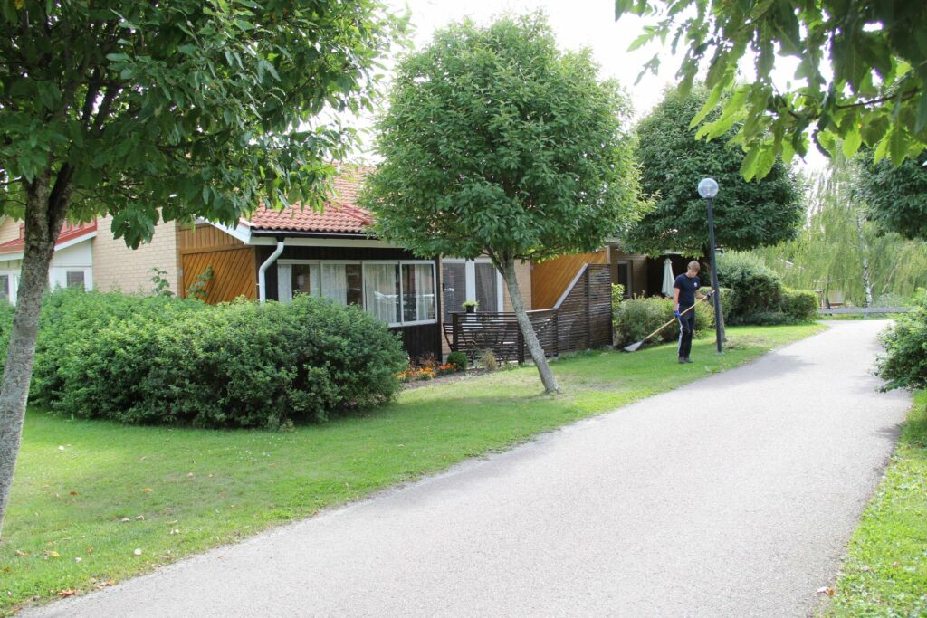 Radhus med en fastighetsskötare från Hallstahem som krattar löv