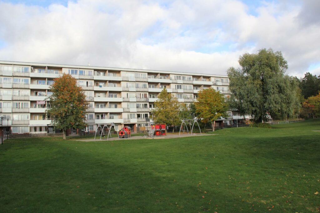 Stor grönyta med lekpark samt lägenhetshus bakom